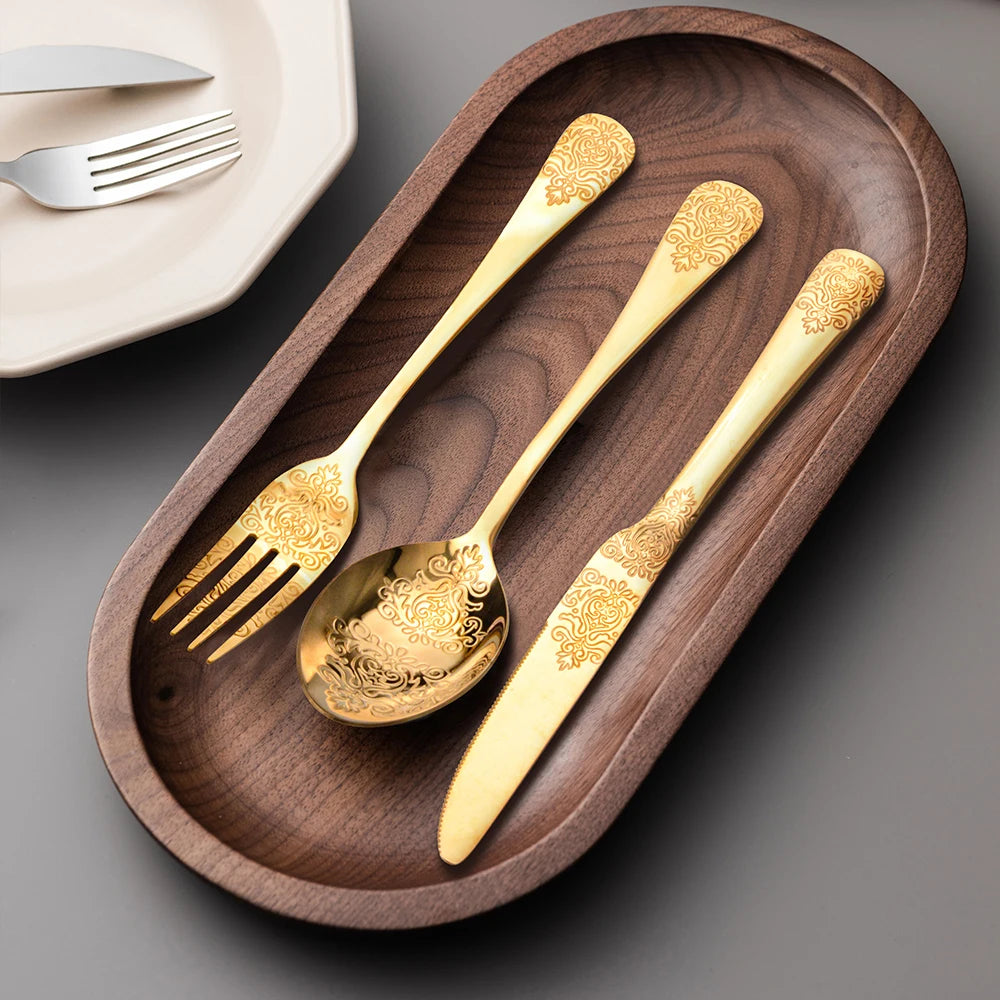 Stainless steel gold flatware set by MC THE BLACK DIAMOND, including forks, knives, and spoons arranged on a dining table.