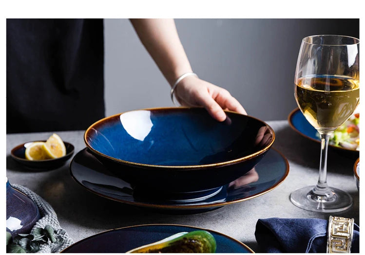 Deep blue ceramic dinnerware set by MC THE BLACK DIAMOND, including plates and bowls arranged on a table.