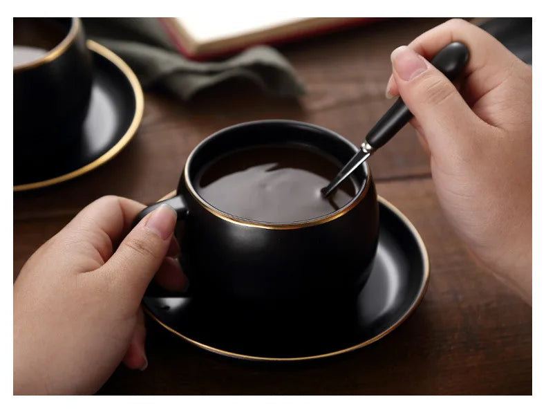 Creative matte black ceramic coffee cup with gold border and matching saucer, modern design for café or home decor.