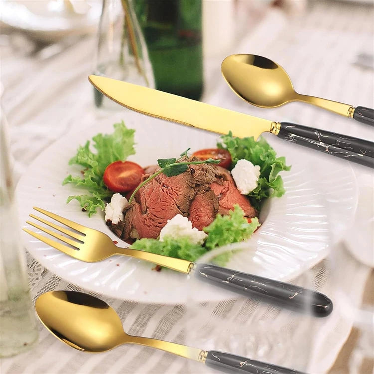 Set of stainless steel flatware including knives, forks, and spoons by MC THE BLACK DIAMOND, arranged on a table.
