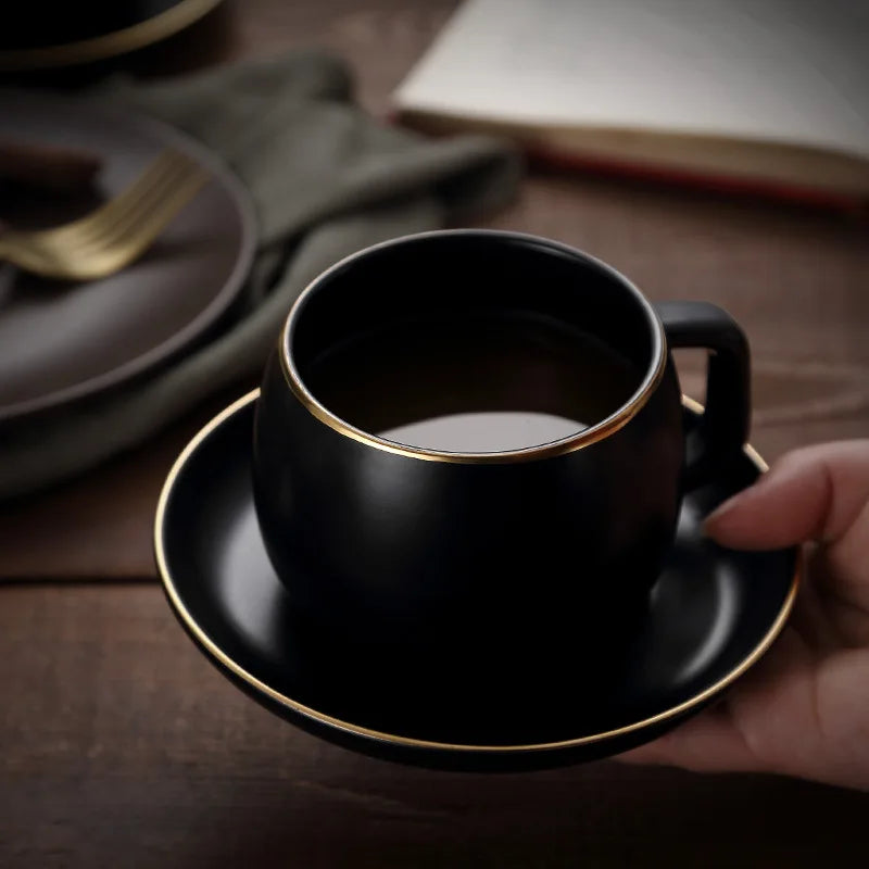 Creative matte black ceramic coffee cup with gold border and matching saucer, modern design for cafe or home use.