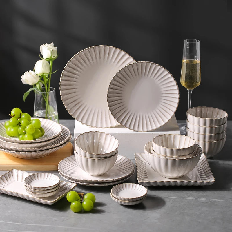 White chrysanthemum-shaped ceramic dinnerware set by MC THE BLACK DIAMOND, includes plates, bowls, and cups with floral design.