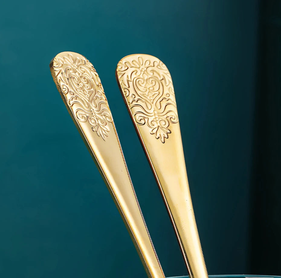 Stainless steel gold flatware set with forks, knives, and spoons from MC THE BLACK DIAMOND, displayed on a dining table.