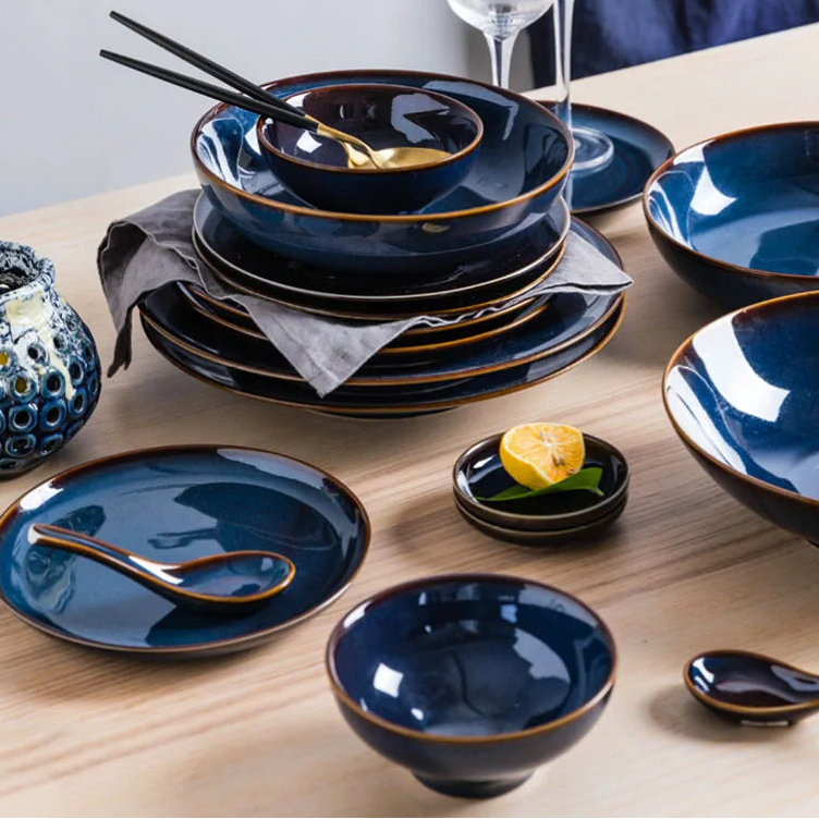 Deep blue ceramic dinnerware set by MC THE BLACK DIAMOND, includes plates and bowls arranged on a table.
