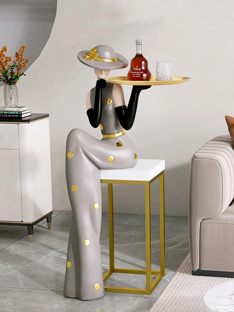 Decorative figurines on a tray placed on a living room foyer TV cabinet next to a sofa, by MC THE BLACK DIAMOND.