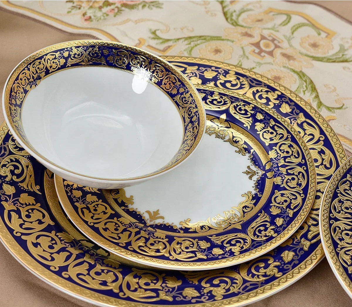Elegant embossed gold rim ceramic dinner set by MC THE BLACK DIAMOND, featuring plates, bowls, and cups with intricate design.