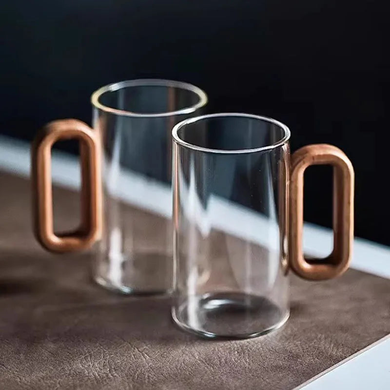 Glass mug with a wooden handle from MC The Black Diamond drinkware set, designed for hot beverages, shown on a neutral background.