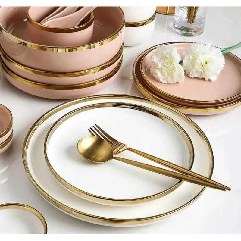 Set of bright white and pink porcelain plates with gold accents from MC THE BLACK DIAMOND, displayed on a kitchen table.