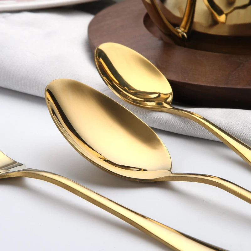 MC THE BLACK DIAMOND golden flatware set with cutlery dishes, featuring polished stainless steel utensils arranged on a white surface.