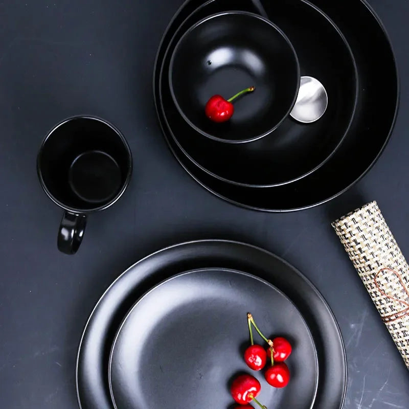 Deep black family dinner set by MC The Black Diamond, featuring plates, bowls, and mugs arranged on a dining table.