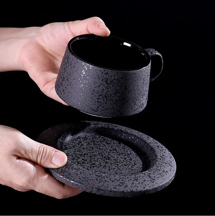 Black ceramic coffee cup with matching saucer, black spoon, and cup holder from MC THE BLACK DIAMOND coffee and tea set.